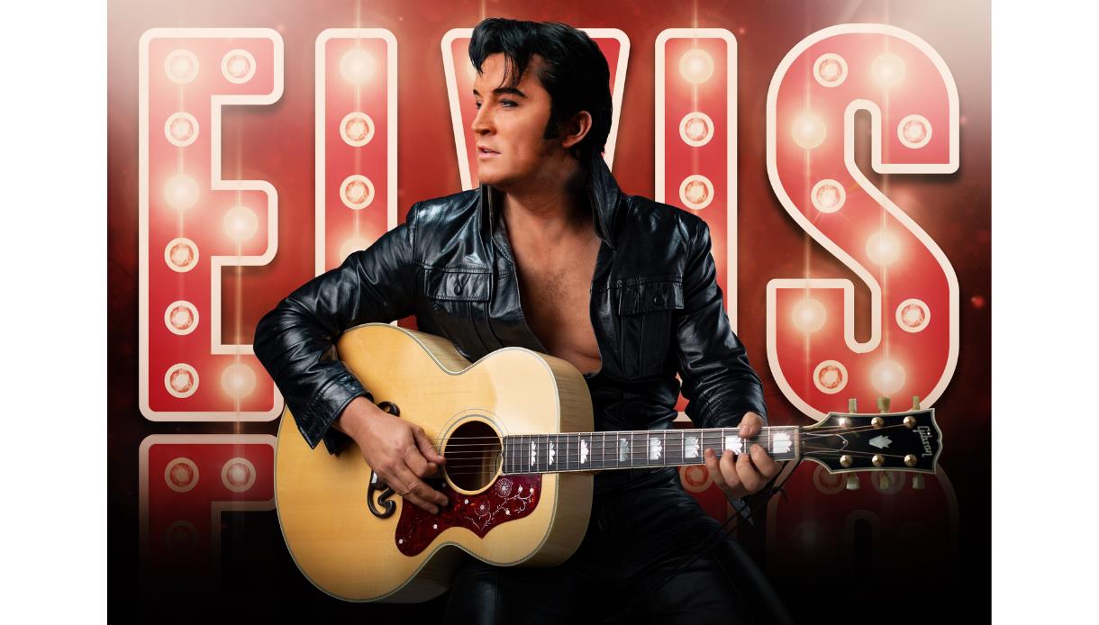 Performer as Elvis in black leather jacket playing guitar before illuminated “ELVIS” sign for Ben Portsmouth show.
