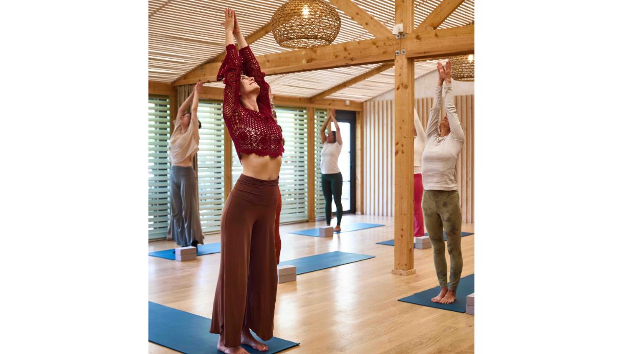 Group yoga session with raised arms in a wooden studio at the Gallivant, Camber during Blue Moonrise class.
