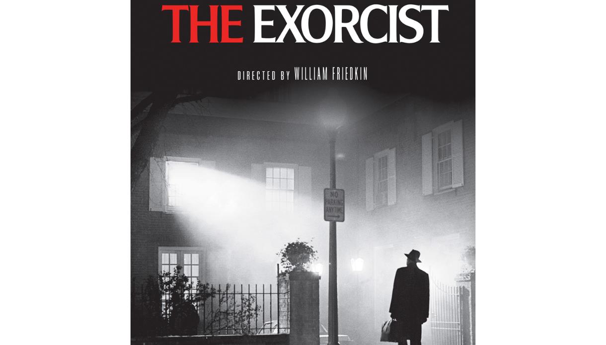 Promotional poster for The Exorcist showing a figure beneath a streetlight outside a misty house at night.
