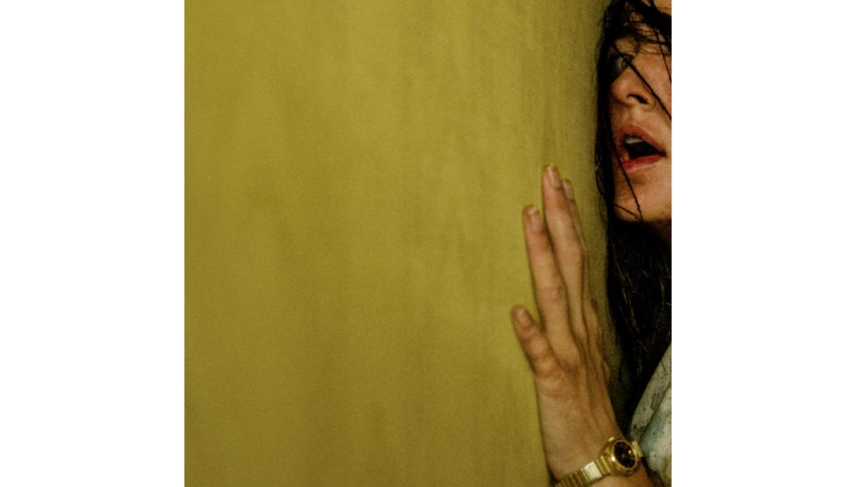 Promotional artwork for Backrooms showing a figure pressed against a yellow wall in a surreal, unsettling setting.