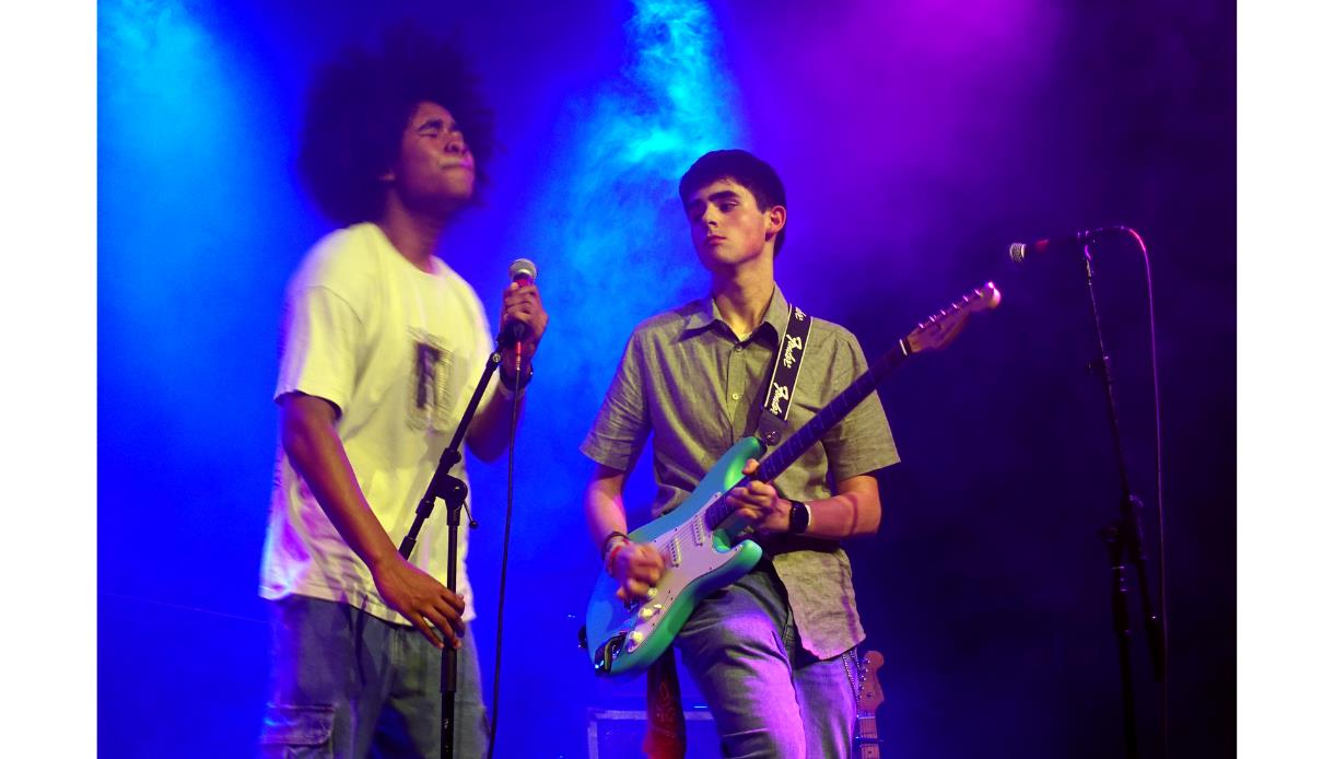 Young musicians performing live on stage at the Create Music Takeover event at the De La Warr Pavilion, under colourful stage lighting.