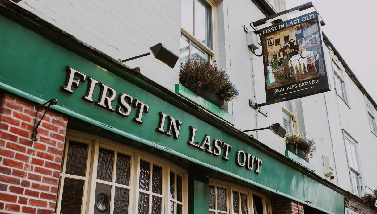 Exterior of the First In Last Out pub in Hastings with traditional signage and green frontage.