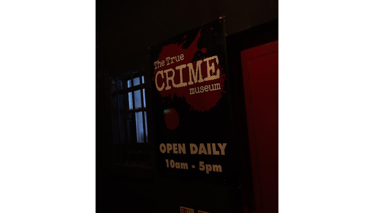 Sign for the True Crime Museum entrance, venue for Bloody Bingo, illuminated against a dark interior backdrop.