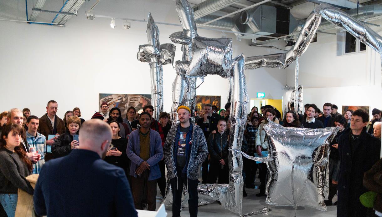 Crowd gathered around silver inflatable sculpture at Flatland Projects gallery opening in Bexhill.