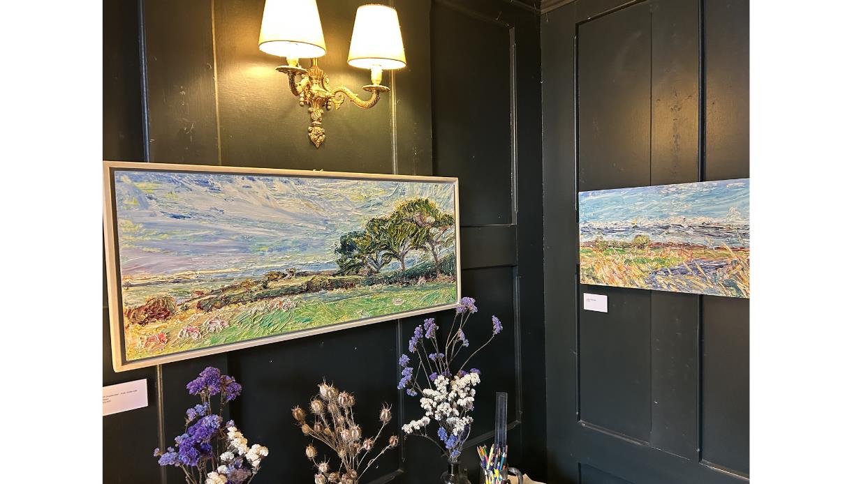 Landscape paintings by Wendy Cox displayed at The Crown in Hastings, with textured scenes of countryside and sky.
