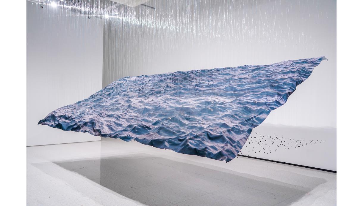 Large suspended wave-like installation with ocean imagery and hanging threads, Miguel Rothschild exhibition at Hastings Contemporary.
