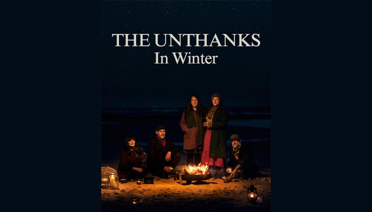 Promotional image for The Unthanks’ album "In Winter", showing five musicians around a beach fire at night.