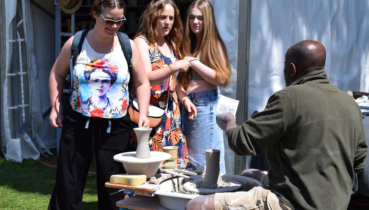 Visitors watch a potter demonstrating wheel throwing at The Sussex Guild Contemporary Craft Show.