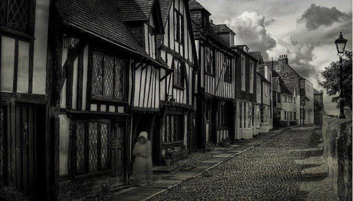 Atmospheric black-and-white view of a historic Rye street with a ghostly figure, promoting the Town Crier's Ghost Walk.