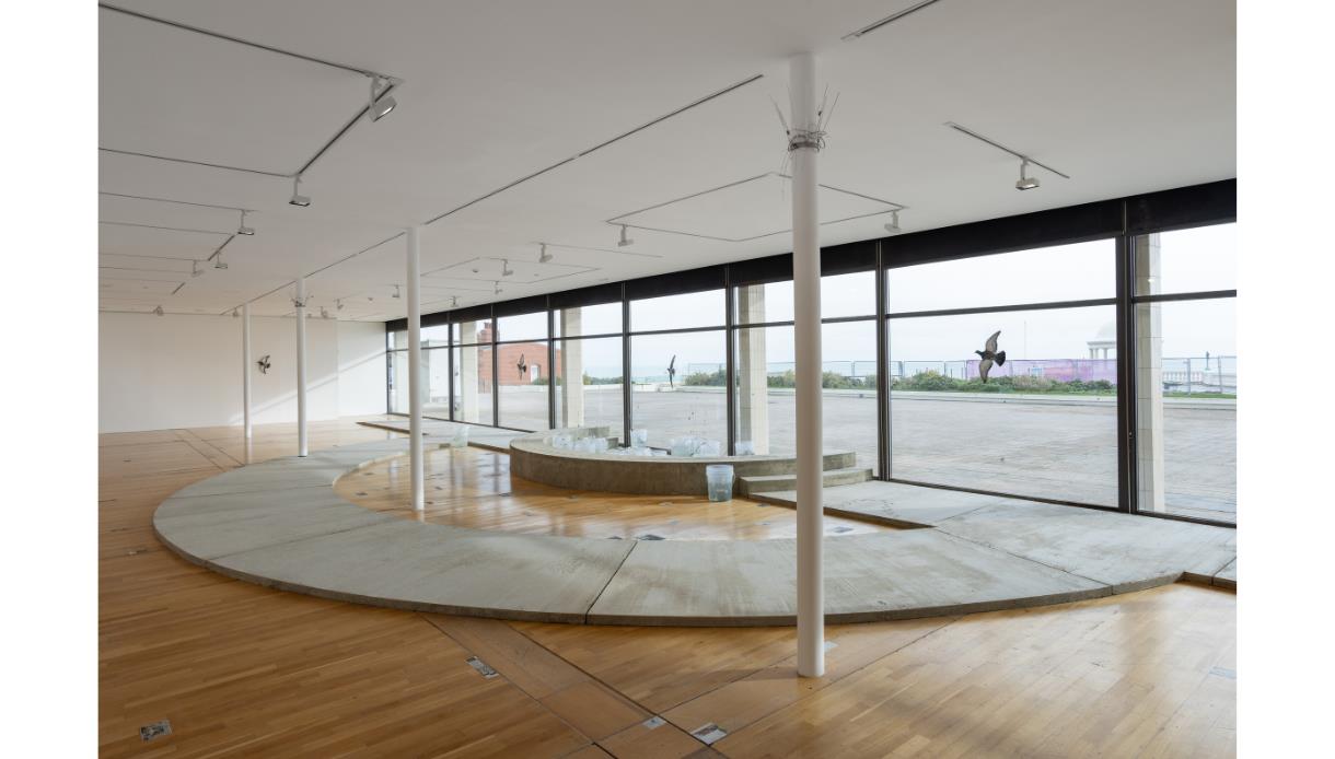 Interior view of De La Warr Pavilion gallery showing Jenine Marsh’s “New Wishes” installation with curved concrete forms and sea views.