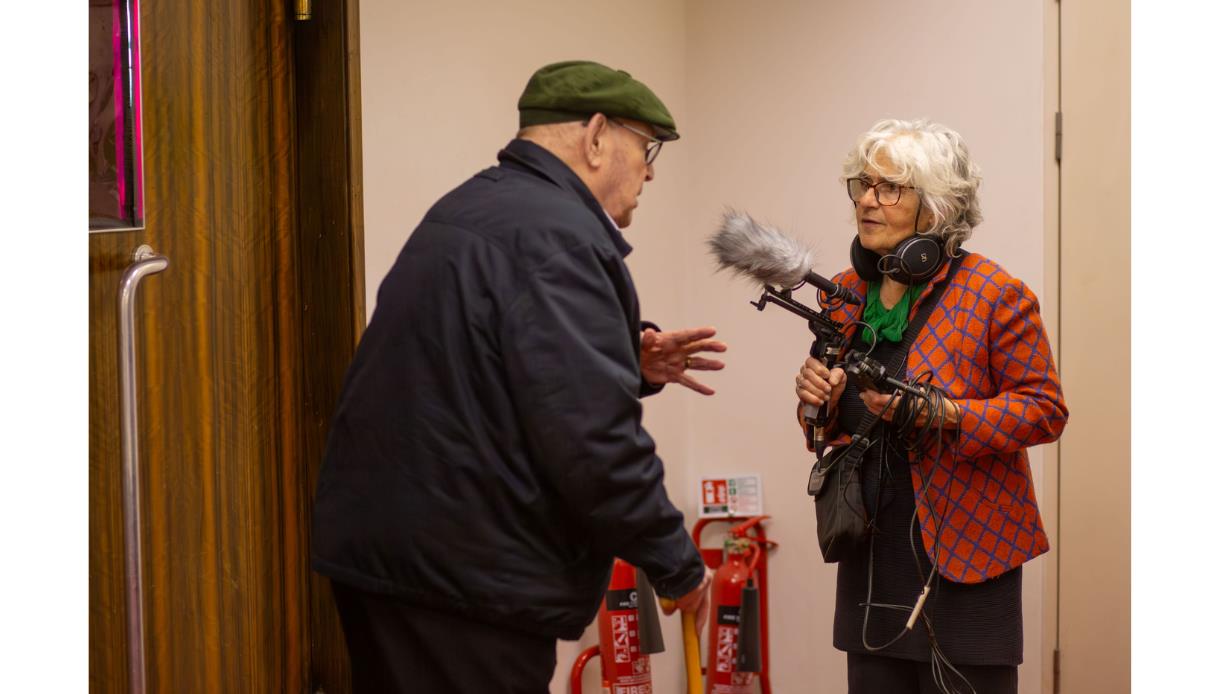 Photo from “90th Birthday Recordings” at De La Warr Pavilion showing an audio recording setup capturing an older participant speaking with a sound rec