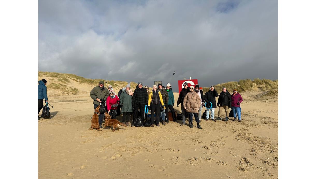 Community group at Camber taking part in The Gallivant’s beach clean, standing on the sand with collected rubbish bags.