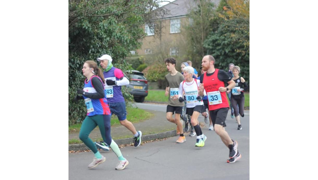 Promotional image for Crowborough 10k & 5k, showing participants running on a road through a residential area.