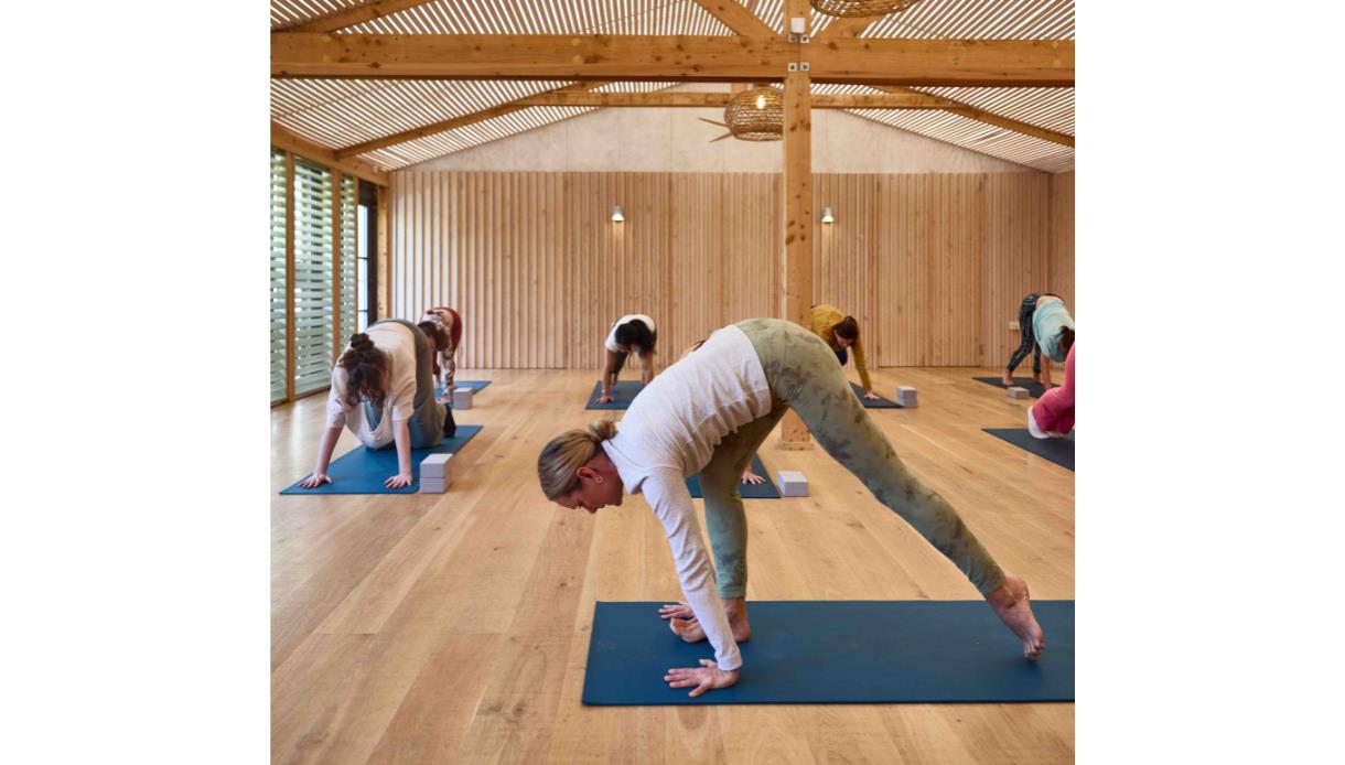 Group practicing yoga poses on mats in a light, wooden studio at The Gallivant in Camber.