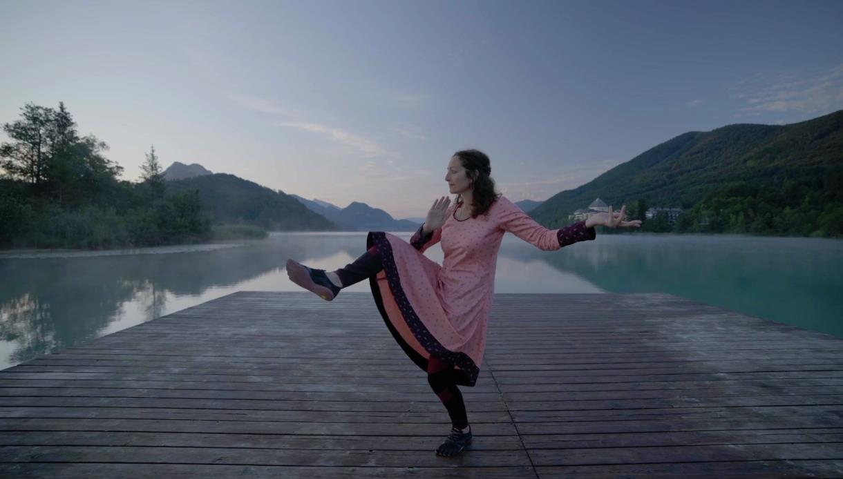 Participant performing a balanced yoga pose on a lakeside dock at the Digestion & Transformation Yoga Masterclass.