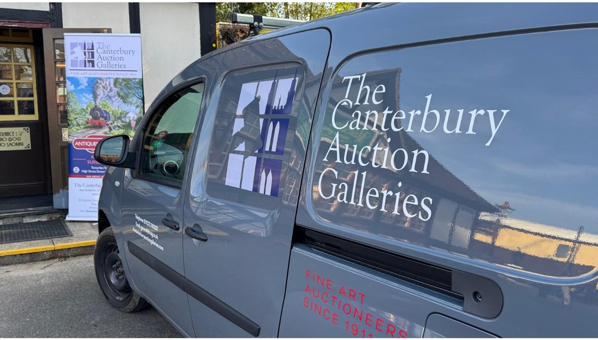 Van branded ‘The Canterbury Auction Galleries’ parked outside a building with a promotional banner by the entrance.
