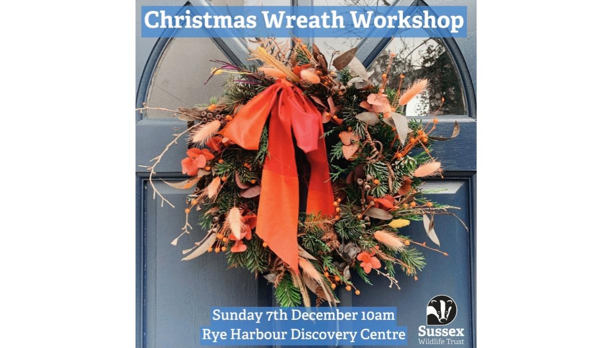 Event image of a seasonal wreath on a navy door. The wreath is textured and wild with fresh greenery, dried foliage, berries, and long ribbon tails in