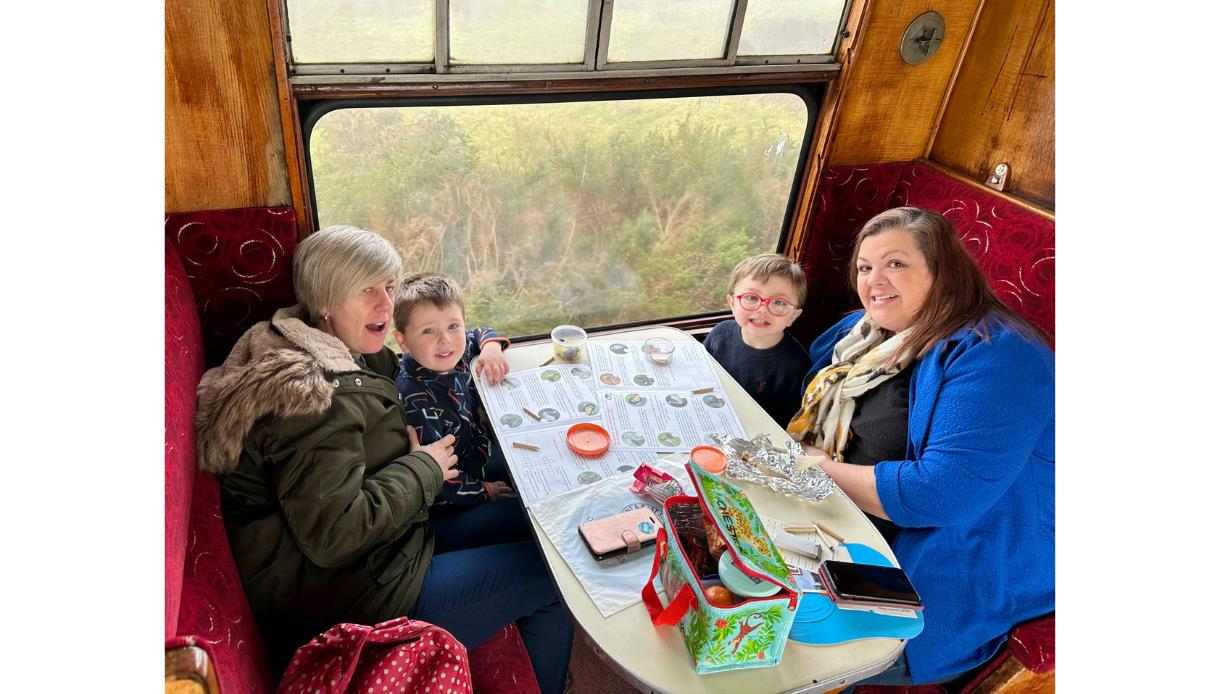 Family sitting in a vintage train booth on the Kent and East Sussex Railway.