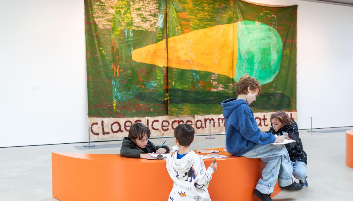 Children enjoying creative activities during a family day at Hastings Contemporary, seated in front of colourful artwork.