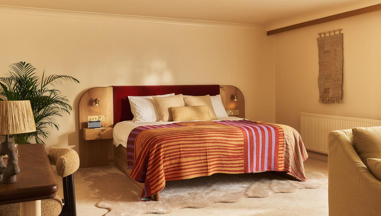 Image shows the inside of one of the bedrooms at Crafted at Powdermills. The Room is bright, light and neutral tones. The bed is in the centre of the
