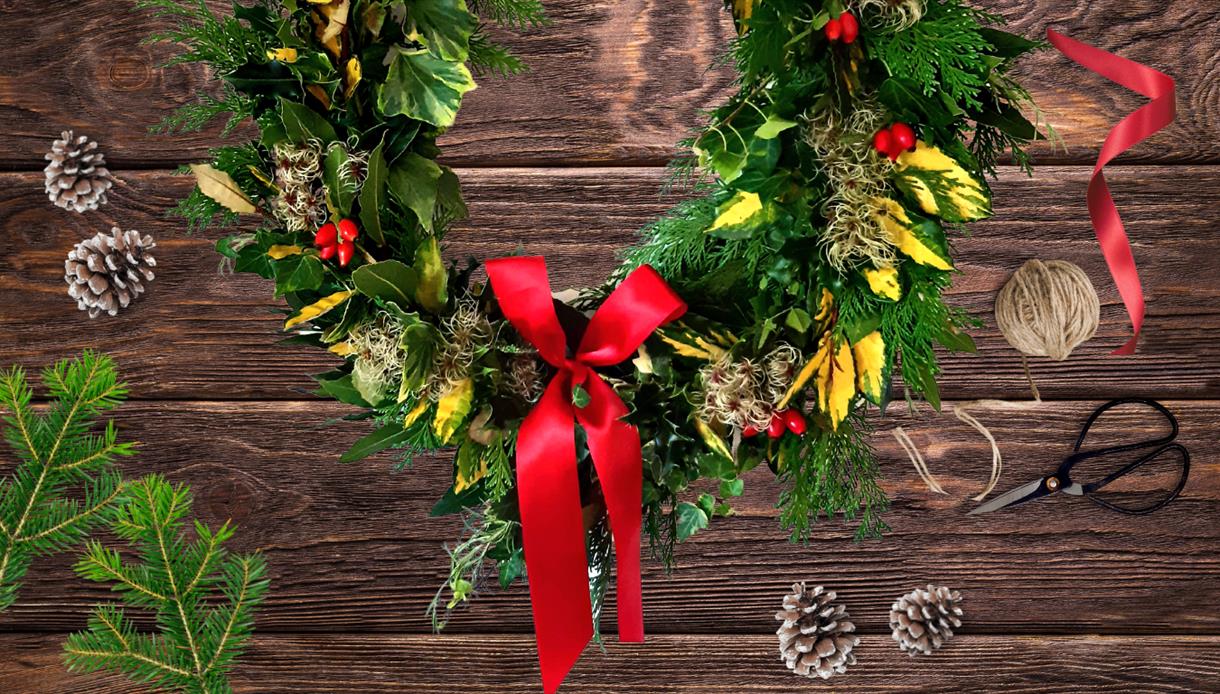 Image shows a christmas wreath decorated with bows, holly and pine cones