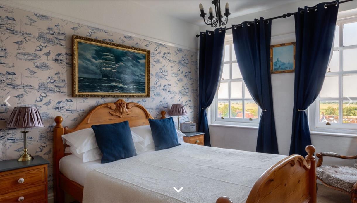 Image shows one of the rooms at The Hope Anchor Hotel. It has two big windows either side of the wall. The room is tastefully decorated in a neutral a