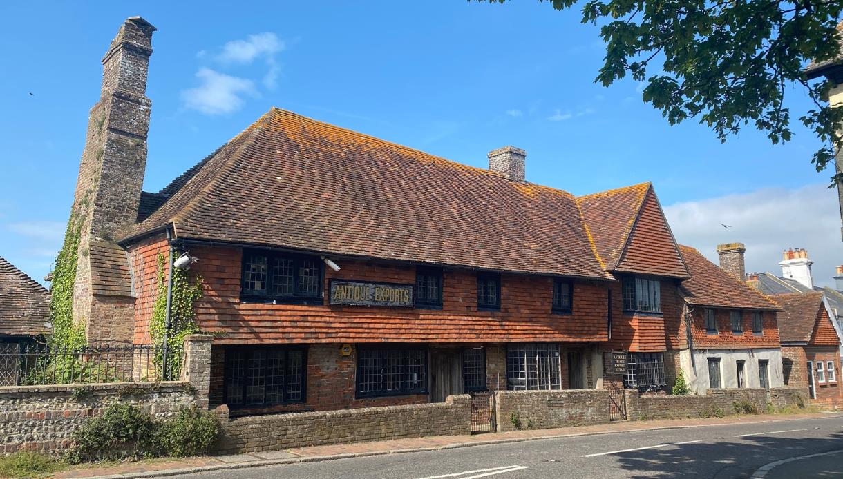 Historic Mint House in Pevensey with timber-framed upper floor and brick lower level, set against a clear sky.