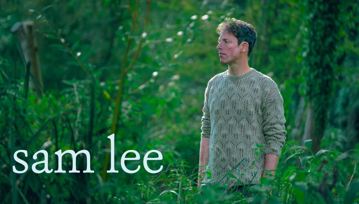 Image shows singer, Sam Lee, in a leafy, green outdoor environment with 'Sam Lee' written