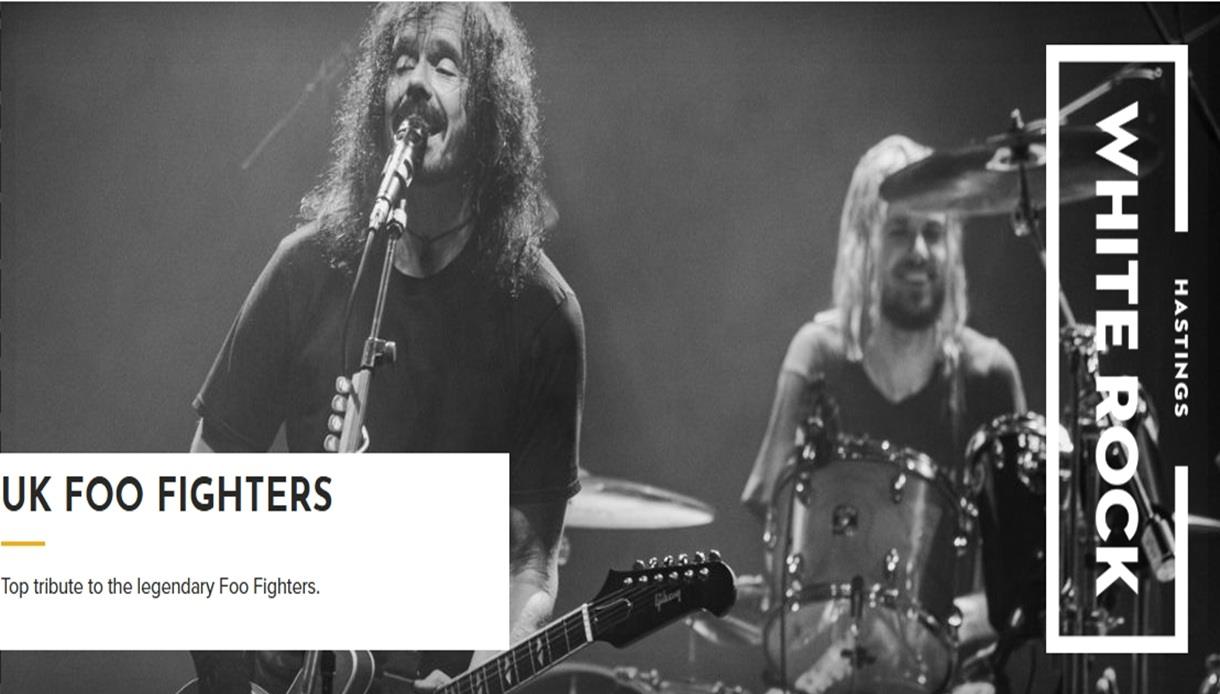Black and white concert image of a Foo Fighters tribute band performing on stage, with drums and guitar, White Rock Hastings logo.