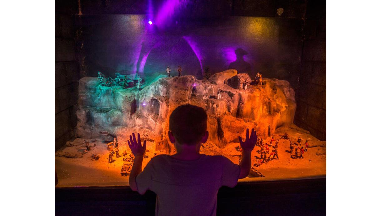 Child looking at a miniature model of smugglers using the caves, at Smugglers adventure Hastings