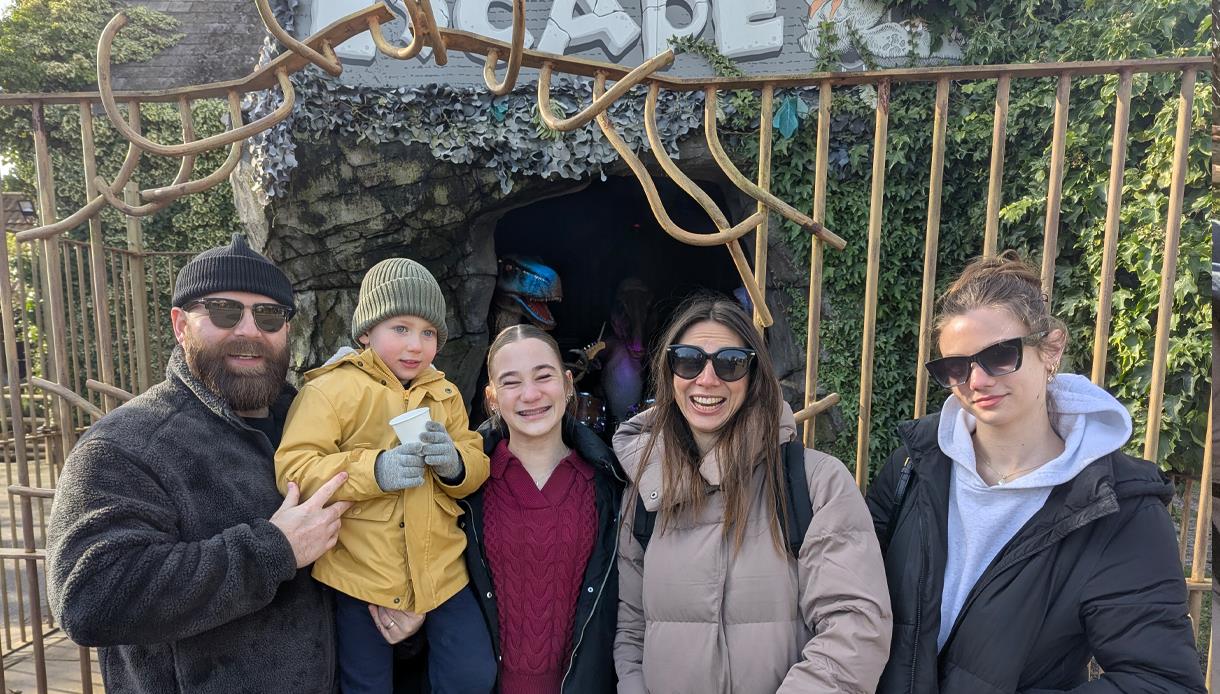 A family standing together at Knockhatch Adventure Park, posing in front of a cave-themed attraction.