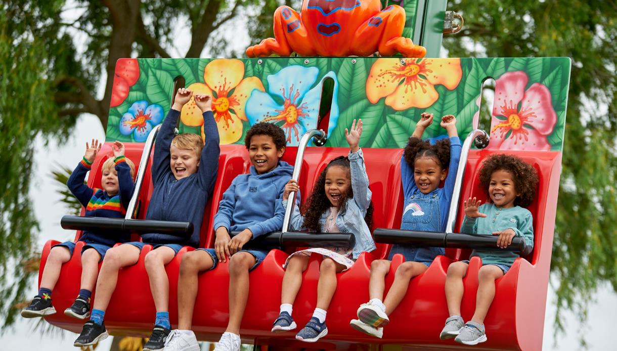 Children enjoying a colourful frog-themed drop ride at Drusillas Park