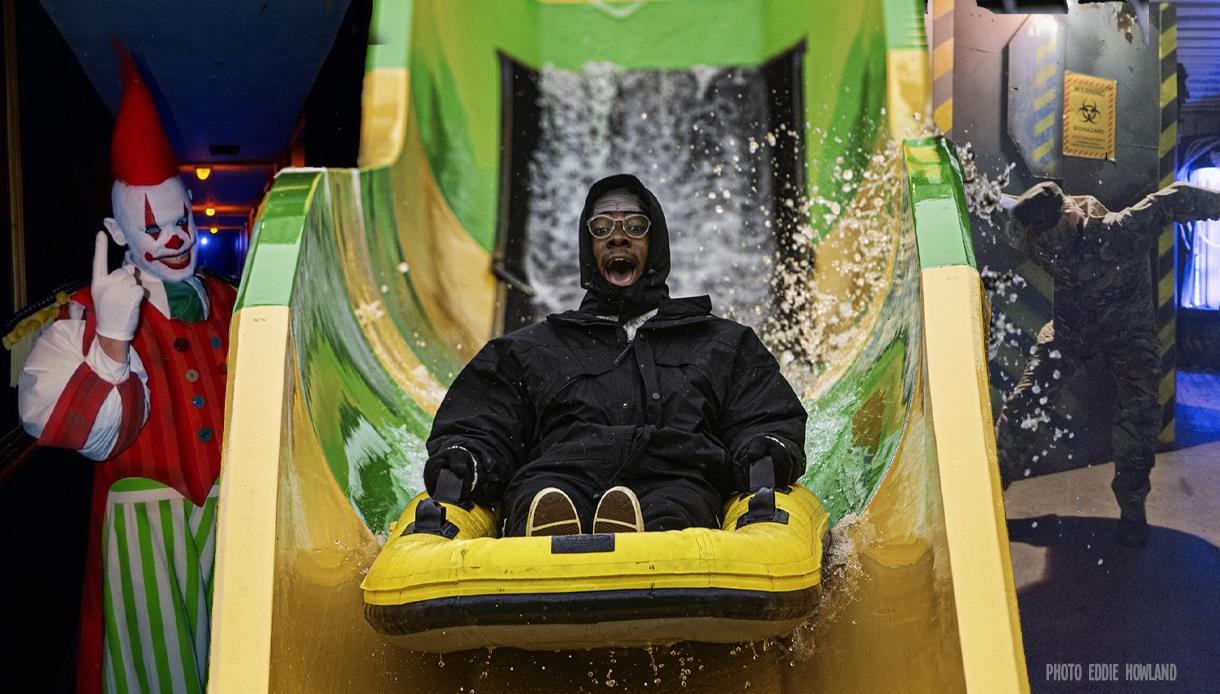 Visitor riding a water slide past Halloween characters during Half Term Horrors at Knockhatch Adventure Park.