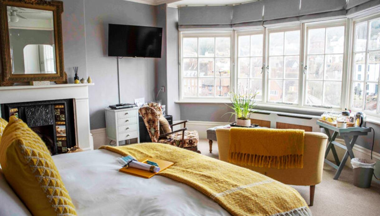 Bright yellow room at The Laindons with large windows overlooking Hastings rooftops and coastline.
