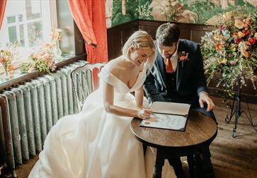 photograph of bride and groom signing a marriage register at The Bell in Ticehurst