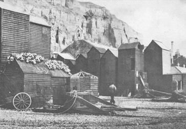 black and white photograph of Hastings Rock-a-nore area with fishing huts on the beach.