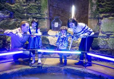 image shows a group of 2 adults and 2 children in Bodiam Castle looking at something off screen.