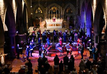 Singers of Hastings Philharmonic Orchestra on stage under coloured lights.