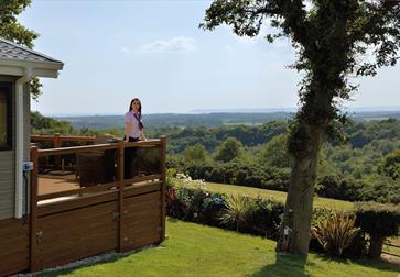 Woman standing on lodge decking enjoying the view  at Crowhurst Park East Sussex