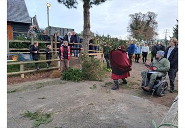 A group gather to watch someone throwing a christmas tree at a previous event.