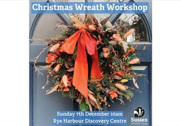 Event image of a seasonal wreath on a navy door. The wreath is textured and wild with fresh greenery, dried foliage, berries, and long ribbon tails in