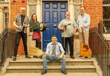 Group of five people posing on outdoor steps holding musical instruments.