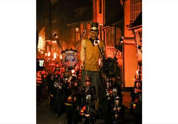 Image shows the parade at Hastings Bonfire. The parade is full of bonfire society members with an effigy.