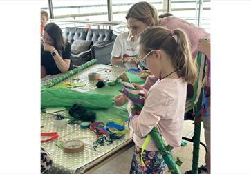 Image shows children and parents at a workshop at the De La Warr Pavilion doing arts and crafts.