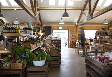 interior of farm shop with beams on ceiling and fresh salad leaves in foreground.