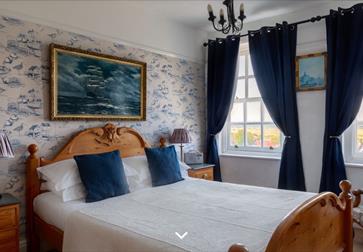 Image shows one of the rooms at The Hope Anchor Hotel. It has two big windows either side of the wall. The room is tastefully decorated in a neutral a