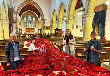 Image shows the inside of St Marys Church with the handmade poppys for the event. There are 4 members of the team standing with the poppys.
