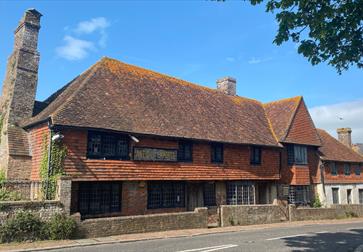 Historic Mint House in Pevensey with timber-framed upper floor and brick lower level, set against a clear sky.