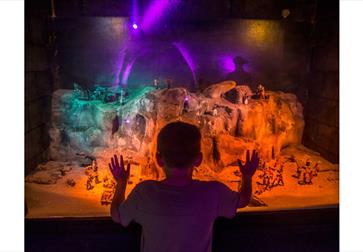 Child looking at a miniature model of smugglers using the caves, at Smugglers adventure Hastings