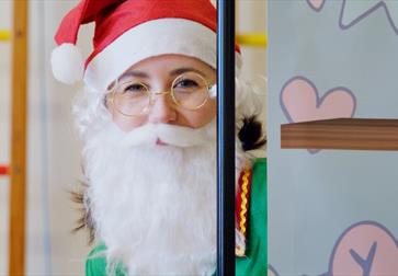 A Christmas elf wears a Santa beard